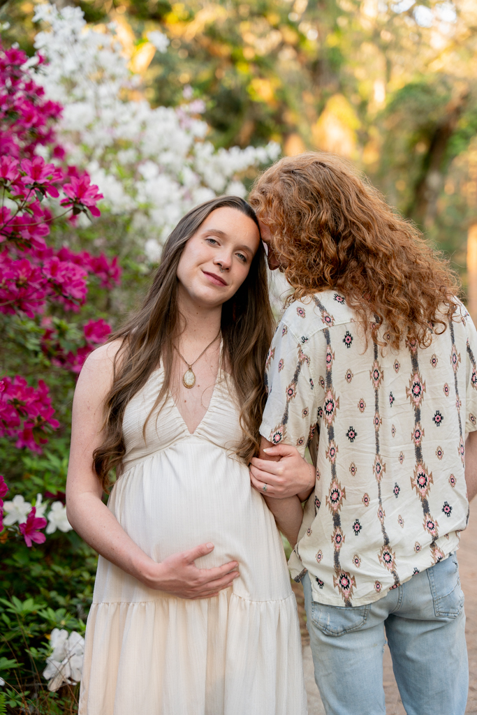 Pregnant woman leaning against a white column on the porch of the historic Wesley House at Eden State Park.
