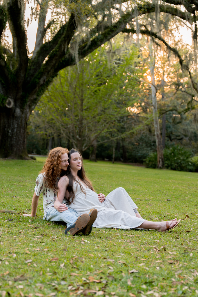 Pregnant woman seated on a bench surrounded by lush greenery and soft light at Eden State Park.