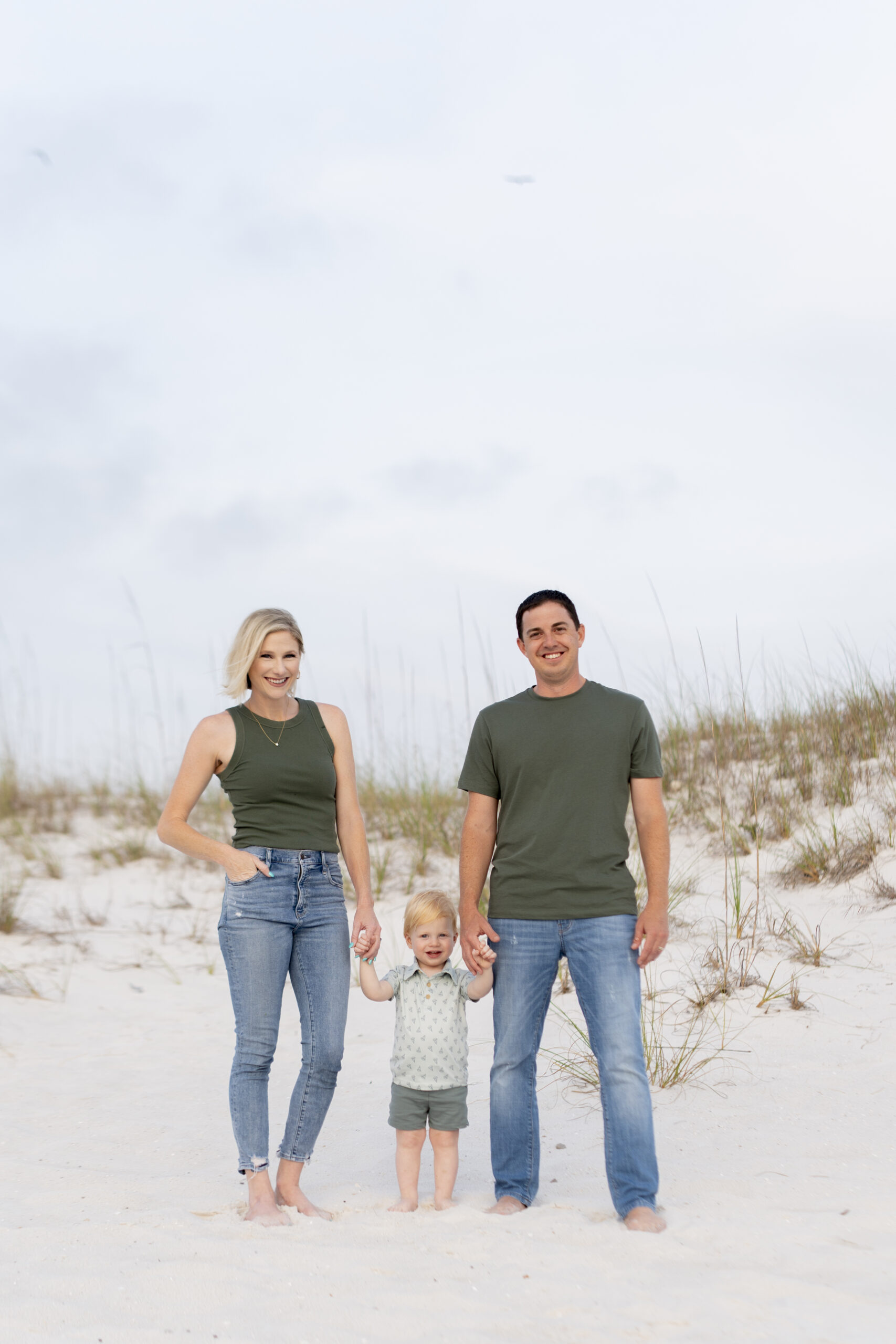 Backlit photo of family holding hands and walking into the sunset at the Destin Jetties.