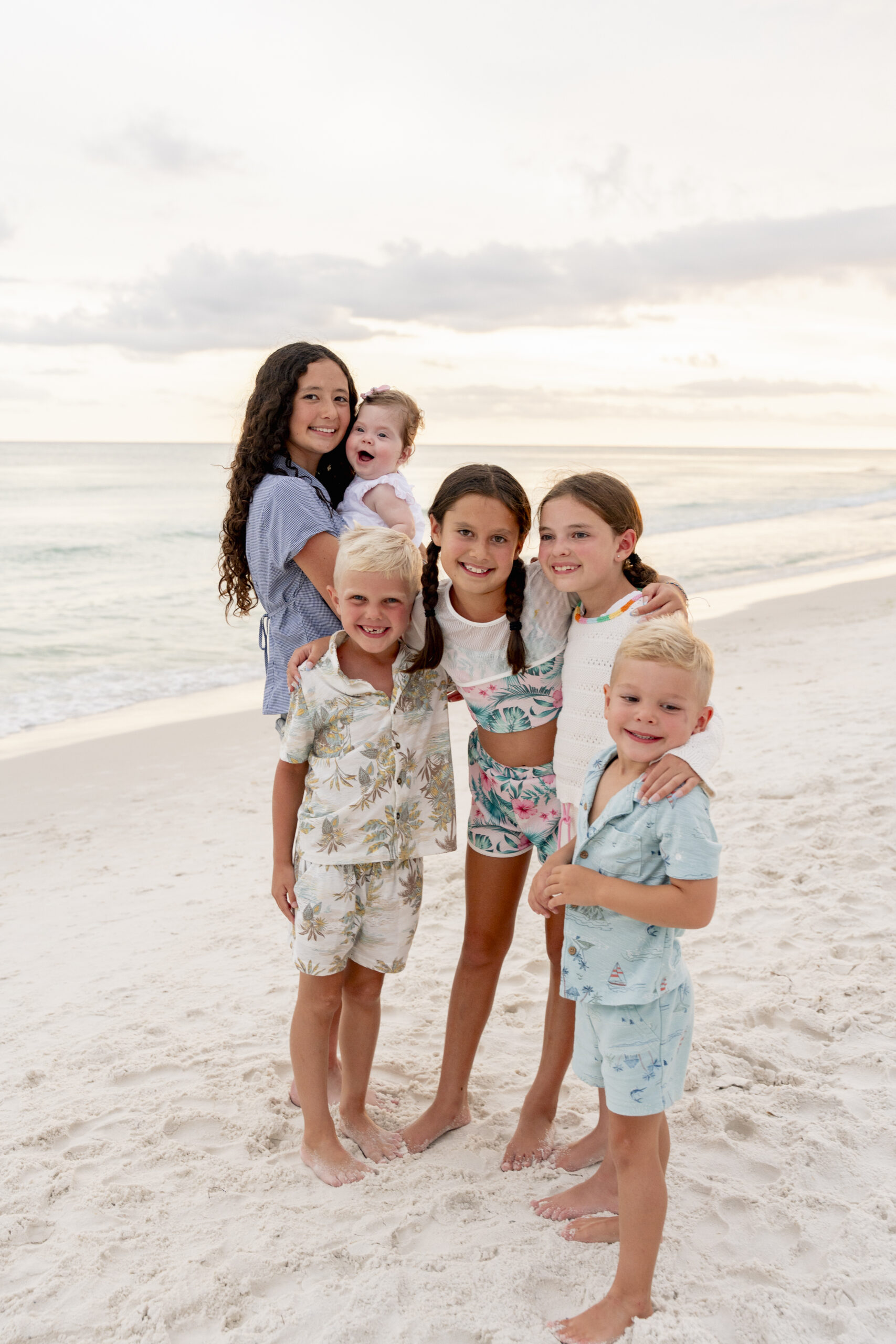 Smiling child playing with seashells in the sand at Inlet Beach with soft-focus dunes behind.