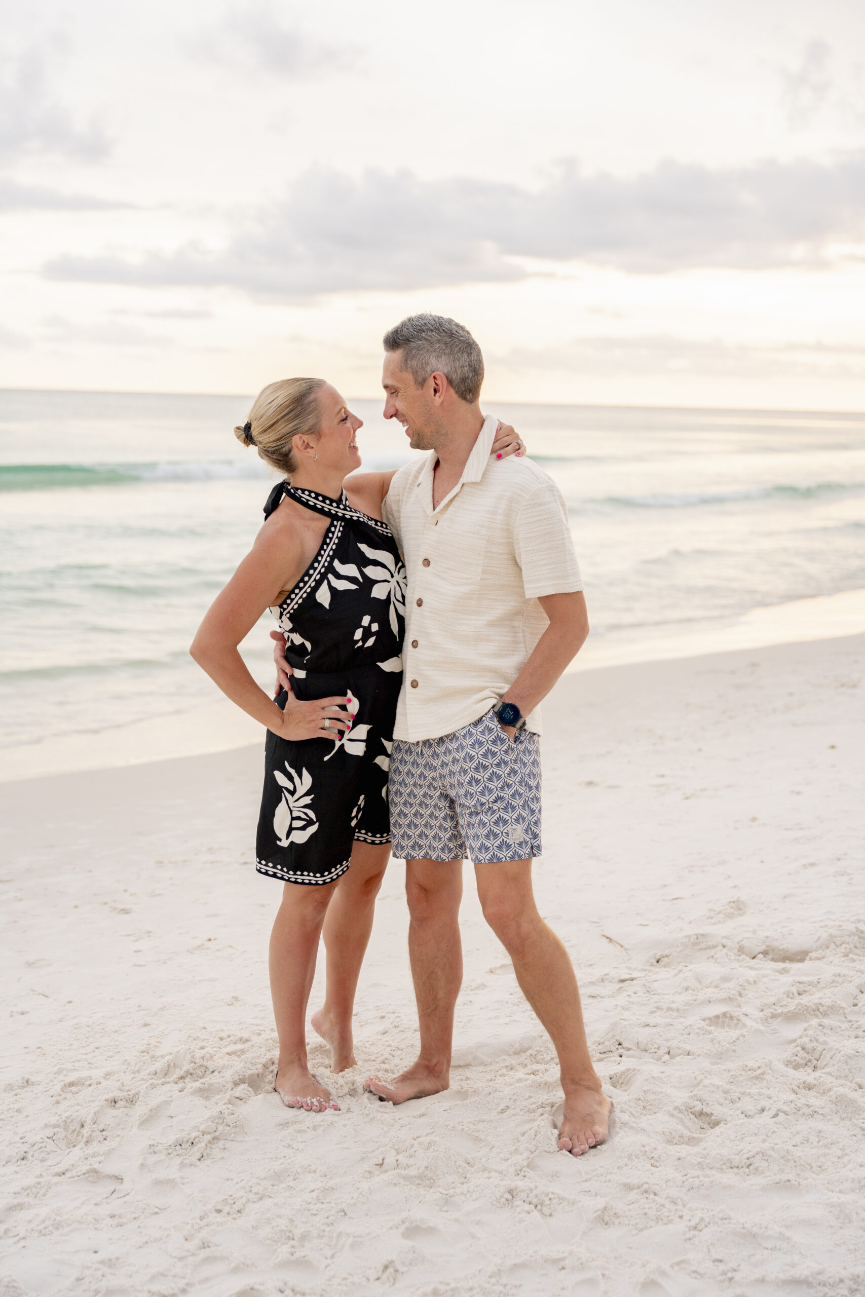 ouple embracing and smiling on the sandy dunes at Inlet Beach with beach grass swaying behind them.