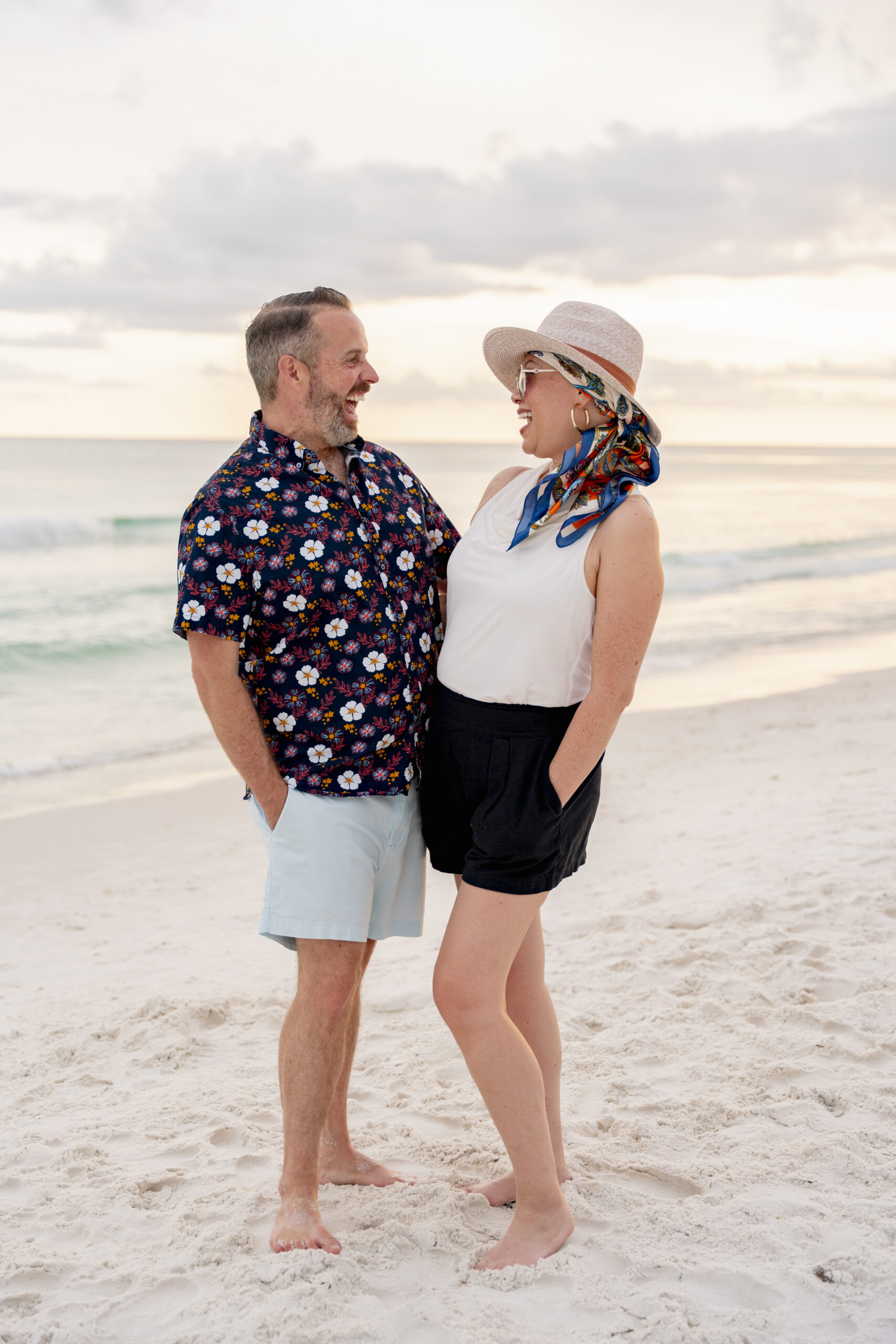 Close-up of a couple standing together on the sand dunes at Inlet Beach, smiling softly at each other.